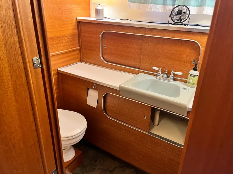 Slide: The Image of 1962 Chris-Craft Constellation bathroom with wooden cabinetry, sink, and toilet. - 28