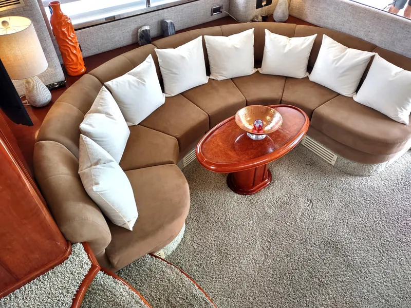 Slide: The Image of Luxurious interior of a 1997 Fairline 66 yacht with a curved sofa and coffee table. - 14