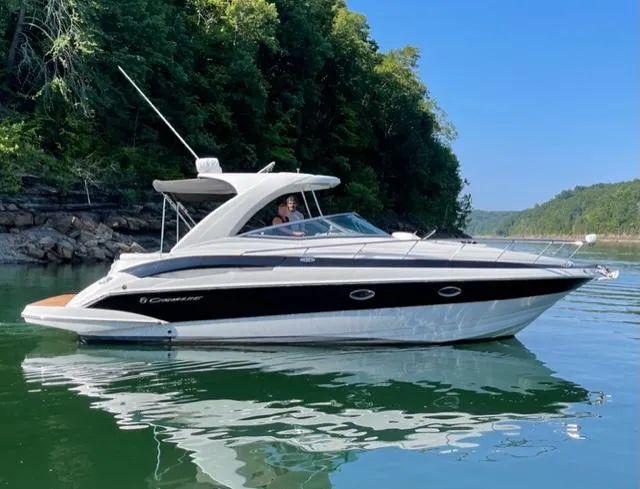 The Image of 2007 Crownline 340 CR boat cruising on a serene lake with lush green trees. - 0