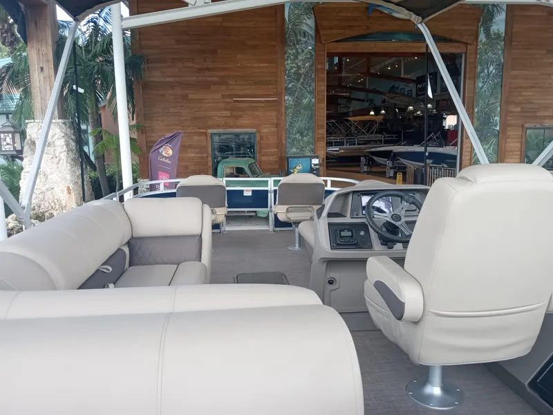 Slide: The Image of 2024 Sun Tracker Fishin' Barge 22 XP3 interior with beige seating and steering console. - 2