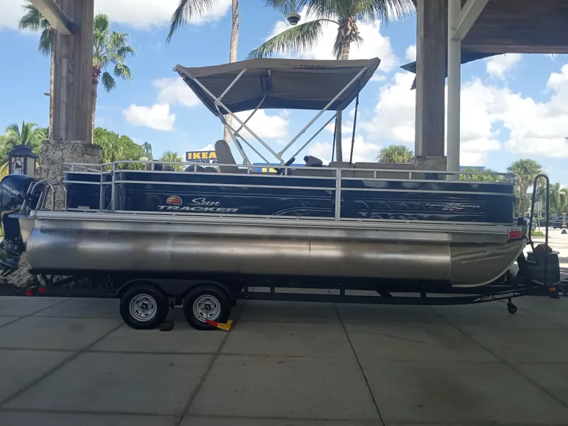 Slide: The Image of 2024 Sun Tracker Fishin' Barge 22 XP3 pontoon boat on a trailer under a canopy. - 4