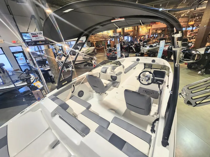 Slide: The Image of 2024 Tahoe T21 boat interior at a showroom, featuring seating and steering console. - 2