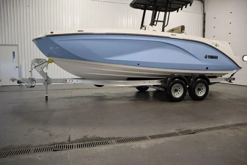 Slide: The Image of 2024 Yamaha Boats 222 FSH Sport in a showroom, light blue hull on a trailer. - 25
