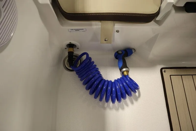 Slide: The Image of 2024 Yamaha Boats 222 FSH Sport with blue coiled hose in deck compartment. - 31