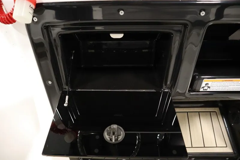 Slide: The Image of 2024 Yamaha Boats 222 FSH Sport storage compartment, black interior, open lid. - 42
