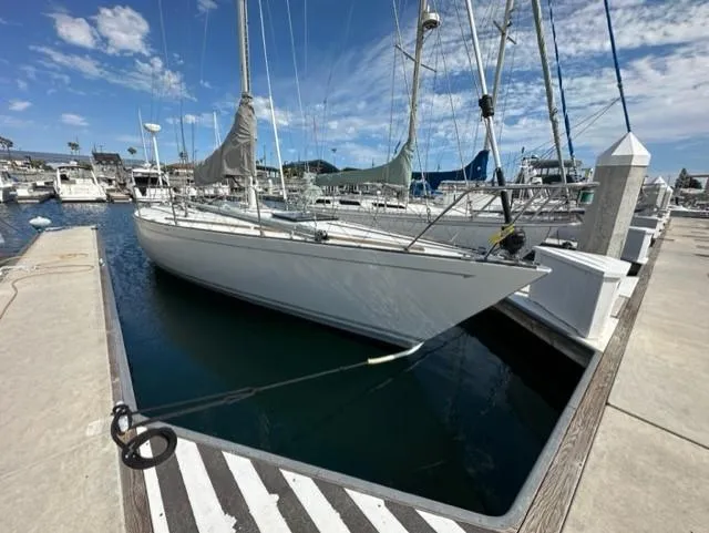 The Image of Eine weiße Segelyacht liegt in einem ruhigen Hafen, umgeben von anderen Booten und einem klaren Himmel. - 0
