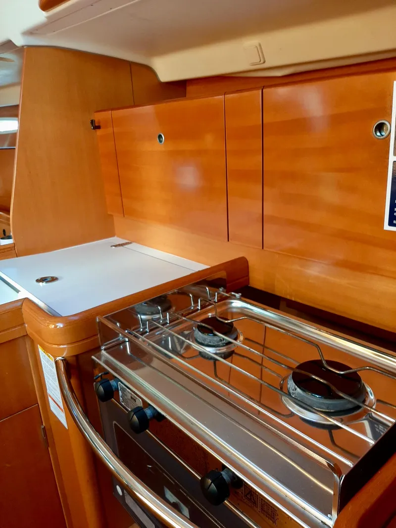 Slide: The Image of 2005 Beneteau First 44.7 yacht kitchen with stove and wooden cabinetry. - 12