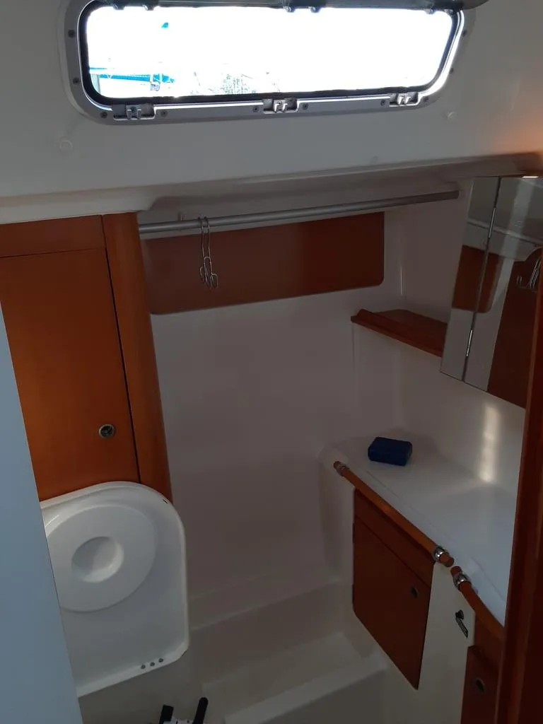 Slide: The Image of 2005 Beneteau First 44.7 yacht bathroom with wooden cabinets and a porthole window. - 18