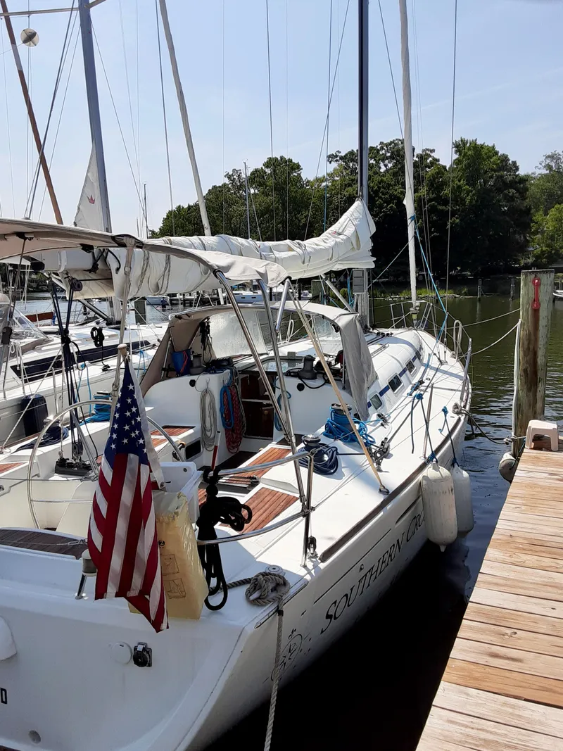 Slide: The Image of 2005 Beneteau First 44.7 sailboat docked, featuring American flag and lush surroundings. - 4
