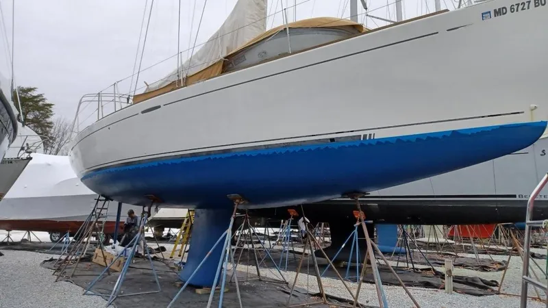 Slide: The Image of 2005 Beneteau First 44.7 sailboat on stands, hull painted blue, in a boatyard. - 5