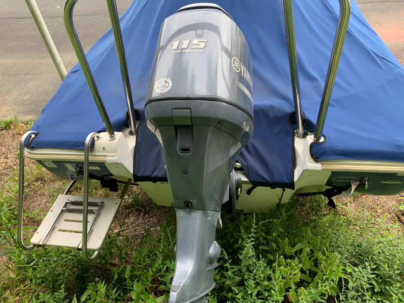 Slide: The Image of 2013 NauticStar 210 Coastal boat with Yamaha 115 outboard motor, covered and parked. - 3
