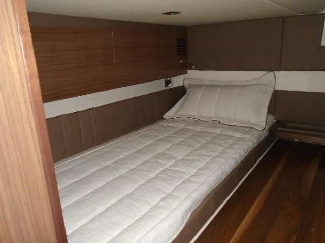Slide: The Image of 2019 Chris-Craft Launch 38 I/O cabin interior with a single bed and wooden accents. - 15