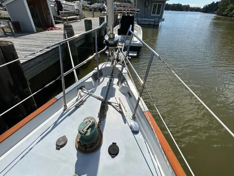 Slide: The Image of 1983 Brewer 42 Center Cockpit sailboat docked by a wooden pier on a calm river. - 11