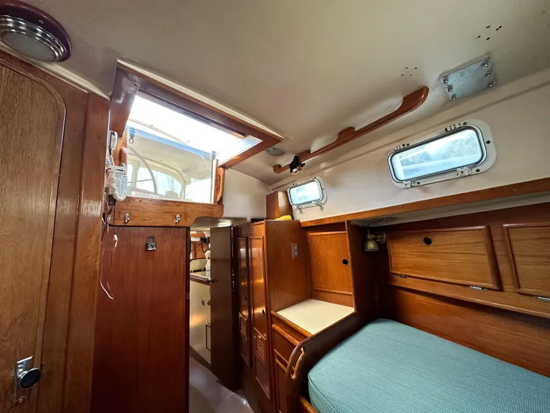 Slide: The Image of 1983 Brewer 42 Center Cockpit interior with wooden cabinetry and cozy sleeping area. - 16