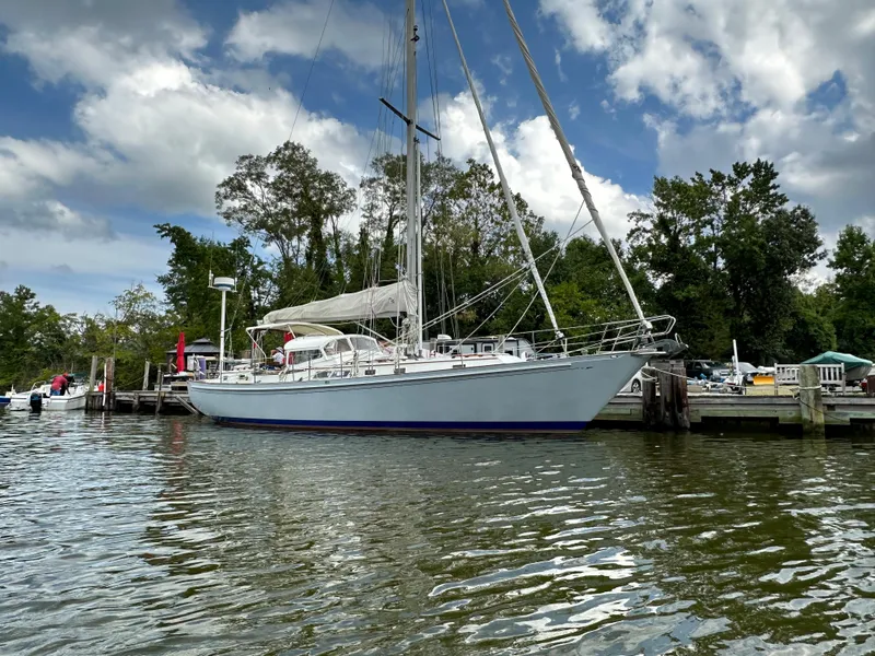 Slide: The Image of 1983 Brewer 42 Center Cockpit sailboat docked on a calm, scenic waterfront. - 2