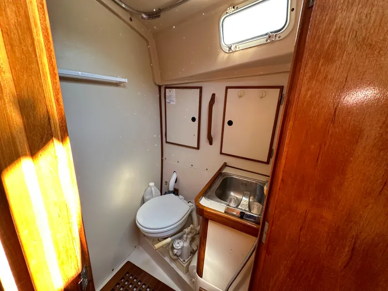 Slide: The Image of 1983 Brewer 42 Center Cockpit bathroom with toilet, sink, and wooden cabinetry. - 21