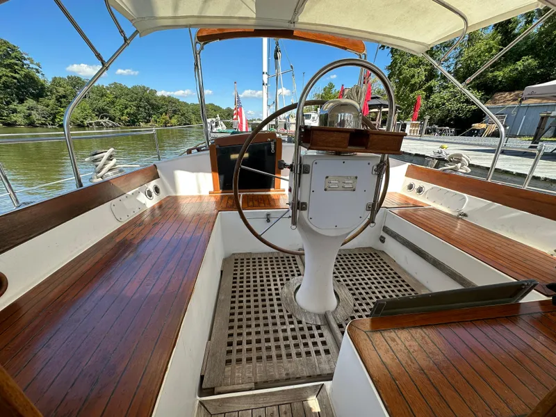 Slide: The Image of 1983 Brewer 42 Center Cockpit sailboat with wooden deck and steering wheel, docked by a river. - 29