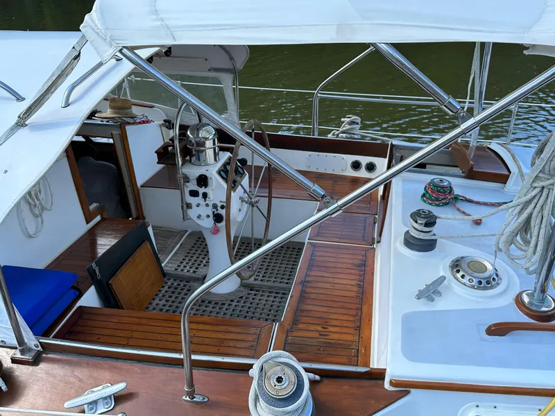 Slide: The Image of 1983 Brewer 42 Center Cockpit sailboat with wooden deck and steering wheel, docked by the water. - 4