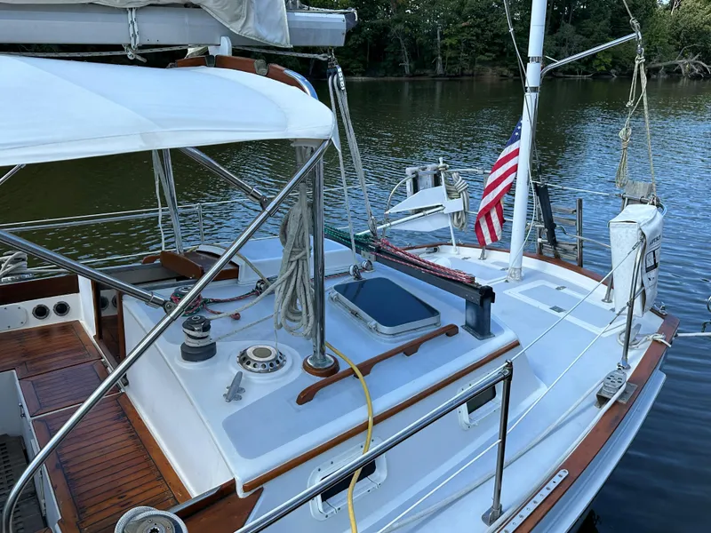 Slide: The Image of 1983 Brewer 42 Center Cockpit sailboat with American flag, docked on calm water. - 5