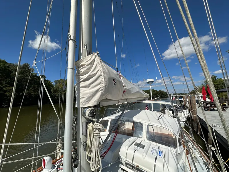 Slide: The Image of 1983 Brewer 42 Center Cockpit sailboat docked, with clear skies and lush surroundings. - 9