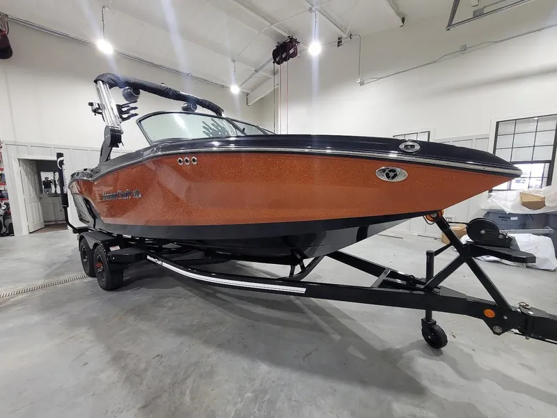 Slide: The Image of 2024 MasterCraft NXT22 boat in a showroom, orange hull, black trailer. - 8