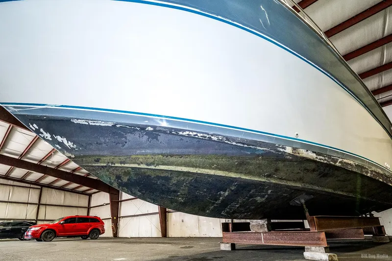 Slide: The Image of 1987 Chris-Craft 320 Amerosport Express boat in storage, with a red car nearby. - 8