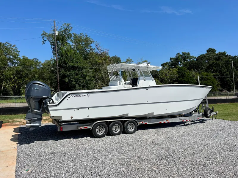 Slide: The Image of Freeman 37VH 2021 boat on trailer, parked on gravel, with trees in the background. - 3