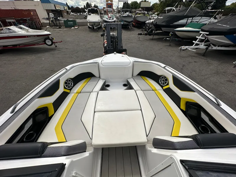 Slide: The Image of 2020 Yamaha 212X jet boat interior with yellow accents, docked among other boats. - 15