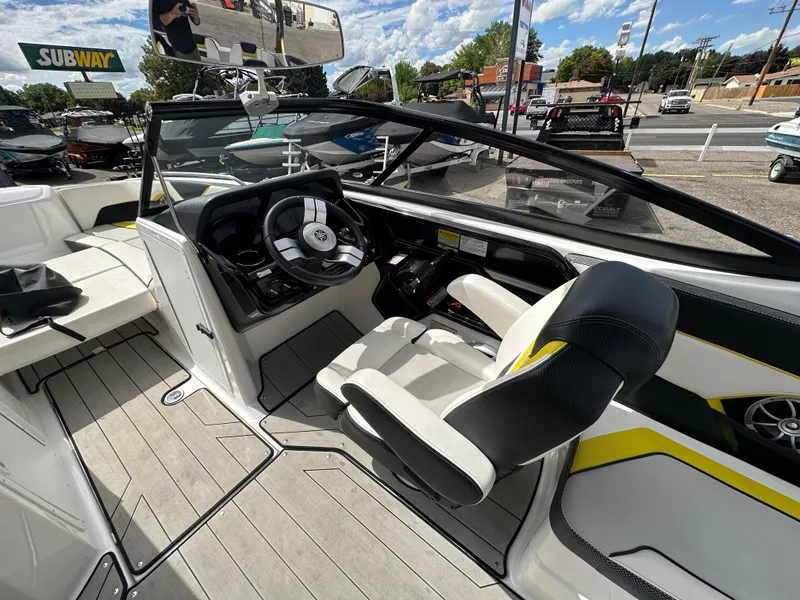 Slide: The Image of 2020 Yamaha 212X jet boat interior with steering wheel and seating, parked outdoors. - 17