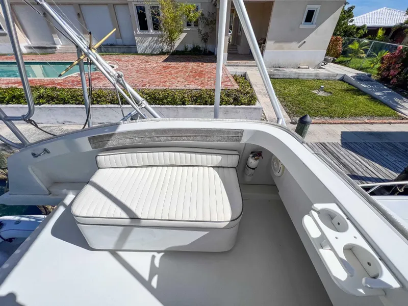 Slide: The Image of 2000 Luhrs 400 Convertible boat seating area with white cushioned bench and cup holders. - 11