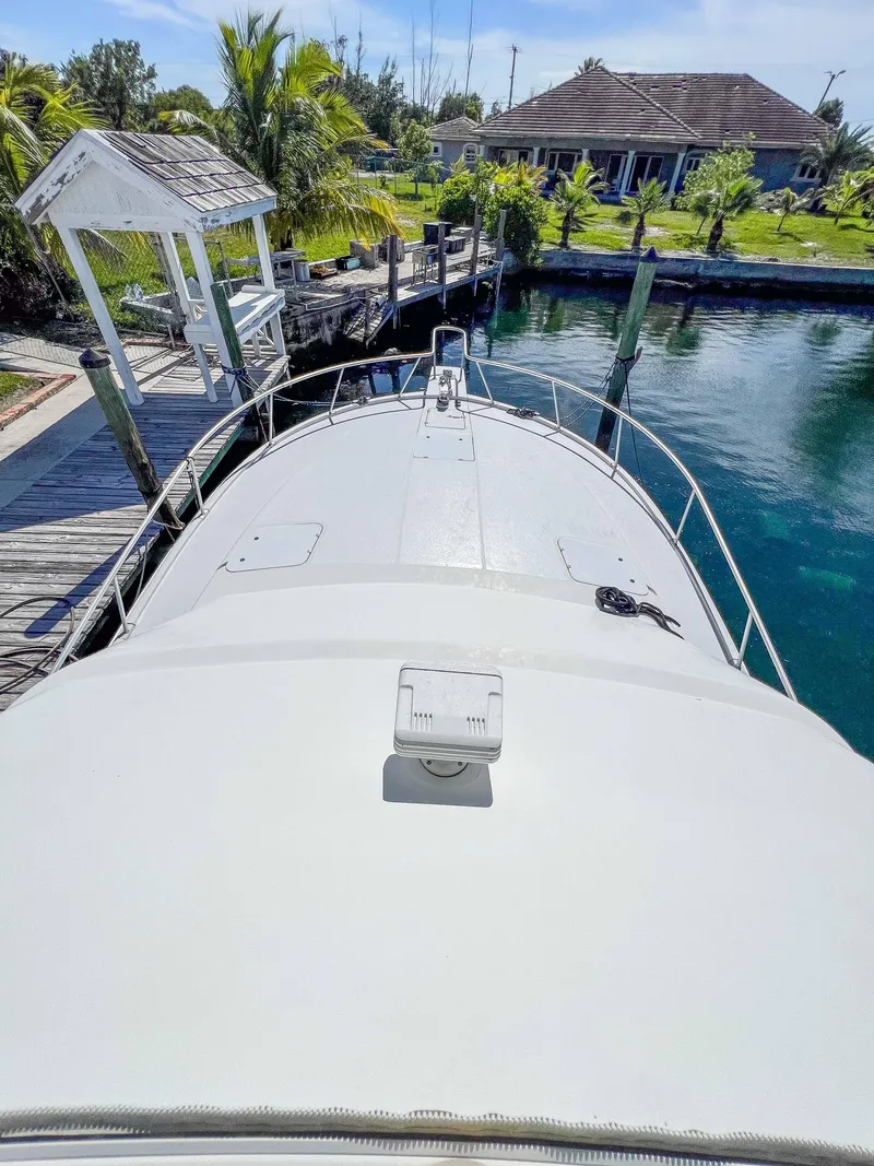 Slide: The Image of 2000 Luhrs 400 Convertible yacht docked near a waterfront property. - 13