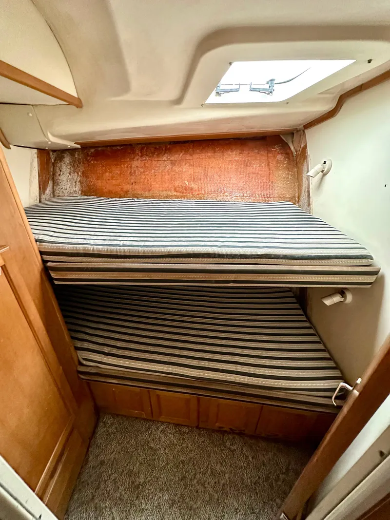 Slide: The Image of 2000 Luhrs 400 Convertible cabin with striped bunk beds and wooden cabinetry. - 32