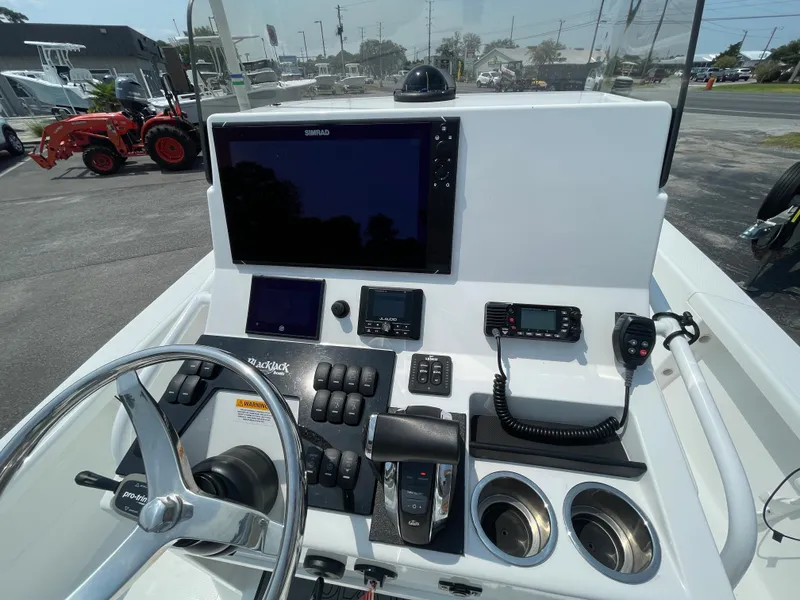 Slide: The Image of 2023 BlackJack 256 Bay boat dashboard with steering wheel, controls, and electronic displays. - 11