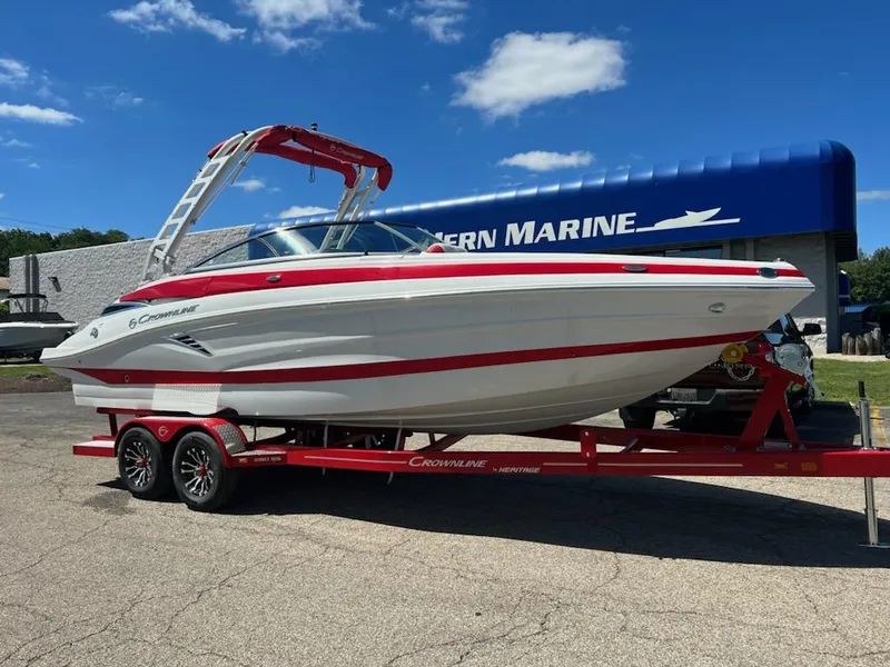 The Image of 2023 Crownline 260 SS boat on a red trailer outside a marine dealership. - 0
