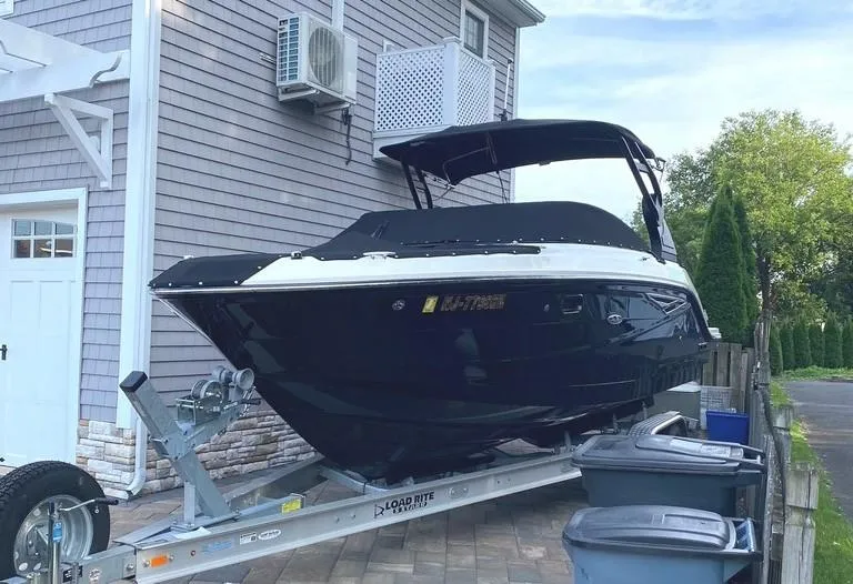 The Image of 2020 Sea Ray SLX 250 boat on trailer in front of house. - 0