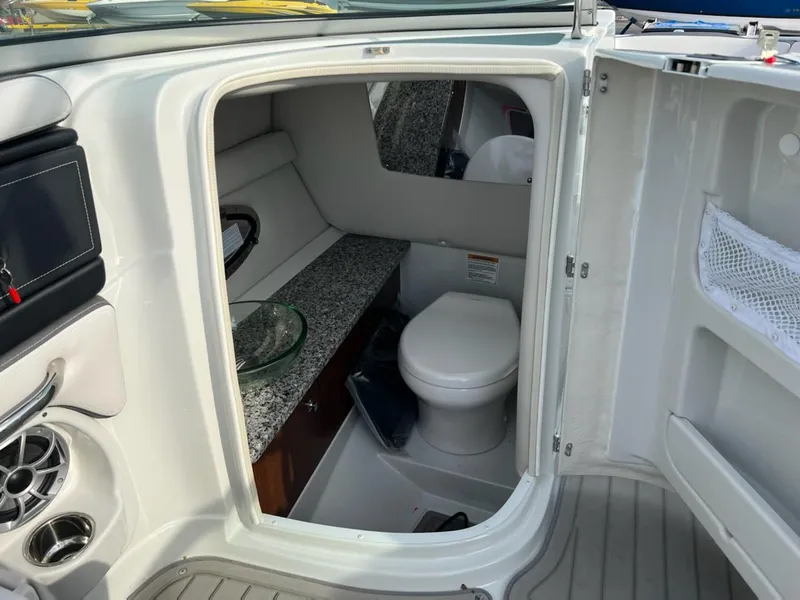 Slide: The Image of 2023 Crownline 260 SS SURF boat interior with a compact bathroom and granite countertop. - 8