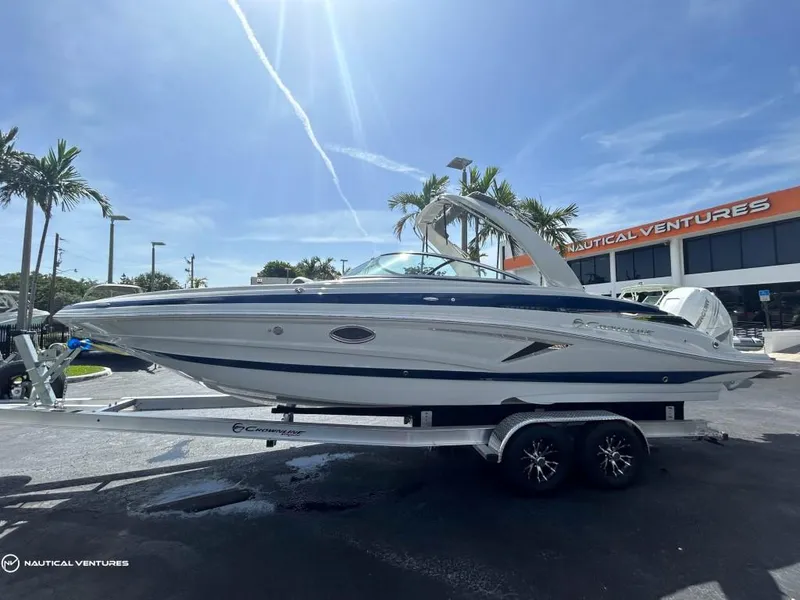 Slide: The Image of 2024 Crownline E290 XS boat on a trailer at Nautical Ventures dealership. - 1