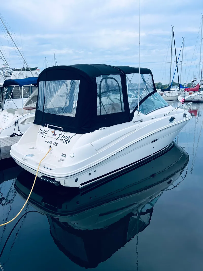 Slide: The Image of 2012 Sea Ray 240 Sundancer boat docked in marina, featuring black canopy. - 2