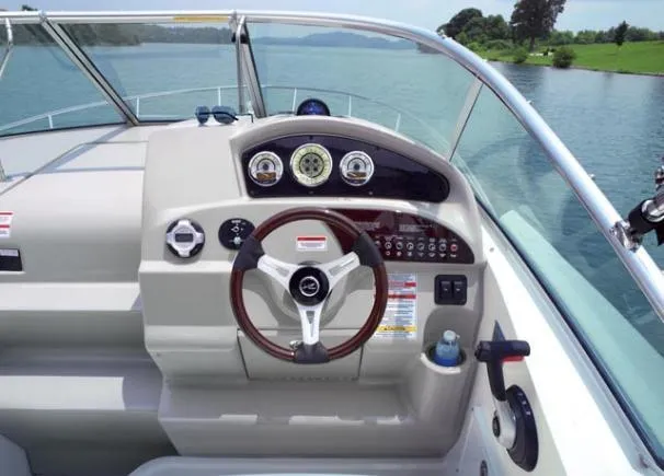 Slide: The Image of 2012 Sea Ray 240 Sundancer helm with steering wheel and gauges on a calm lake. - 5