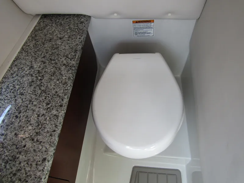 Slide: The Image of 2024 Crownline 270 XSS boat interior with modern toilet and granite countertop. - 25