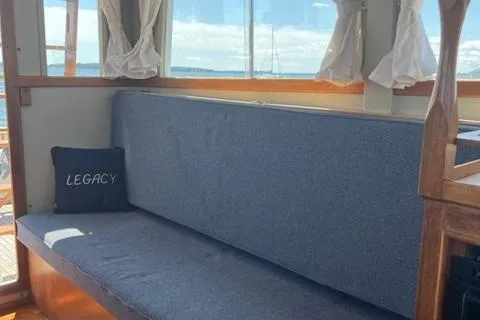 Slide: The Image of 1978 Grand Banks Trawler interior with blue seating and "Legacy" pillow, featuring nautical decor. - 10