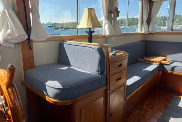 Slide: The Image of 1978 Grand Banks Trawler interior with cozy seating, wooden accents, and scenic window views. - 16