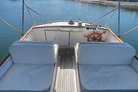Slide: The Image of 1978 Grand Banks Trawler boat interior with white seating and wooden steering wheel. - 41