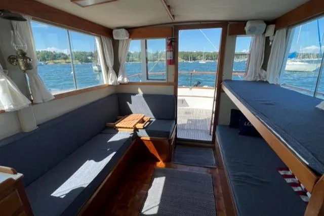 Slide: The Image of 1978 Grand Banks Trawler interior with seating, table, and scenic water views. - 6