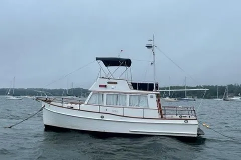 Slide: The Image of 1978 Grand Banks Trawler boat on water, overcast sky, anchored in harbor. - 1