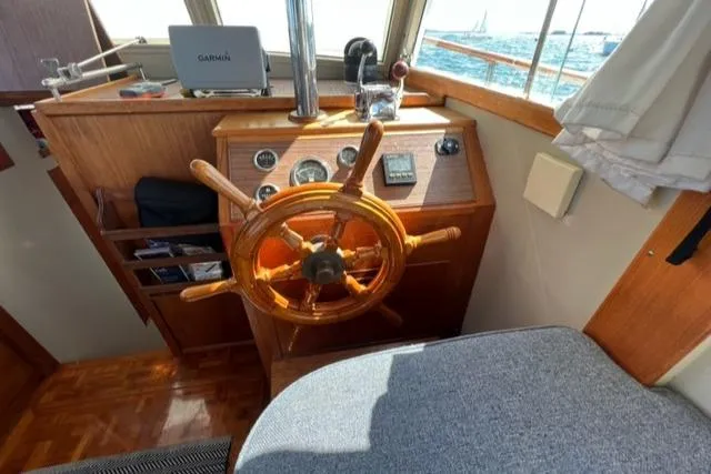 Slide: The Image of 1978 Grand Banks Trawler helm with wooden wheel, navigation instruments, and ocean view. - 15