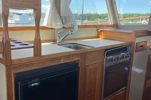 Slide: The Image of 1978 Grand Banks Trawler kitchen with wooden cabinetry, sink, stove, and window view. - 17