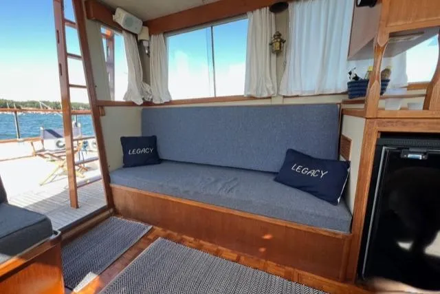 Slide: The Image of 1978 Grand Banks Trawler interior with blue cushions, "Legacy" pillows, and nautical decor. - 3