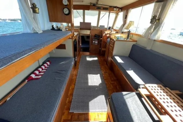 Slide: The Image of 1978 Grand Banks Trawler interior with wooden flooring, seating, and helm, showcasing classic nautical design. - 5