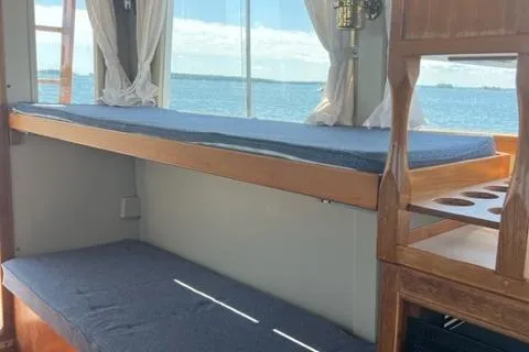 Slide: The Image of 1978 Grand Banks Trawler interior with bunk beds, wooden accents, and ocean view. - 7